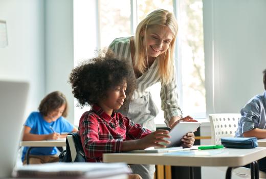 Blonde vrouw helpt kind met kroeshaar in de klas