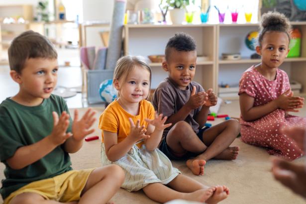 Vier kinderen op de grond klappen in hun handen 