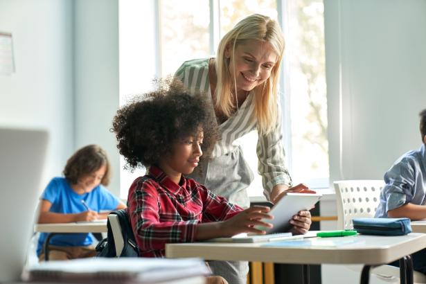 Blonde vrouw helpt kind met kroeshaar in de klas