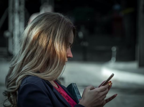 Meisje met blond haar zit op haar telefoon