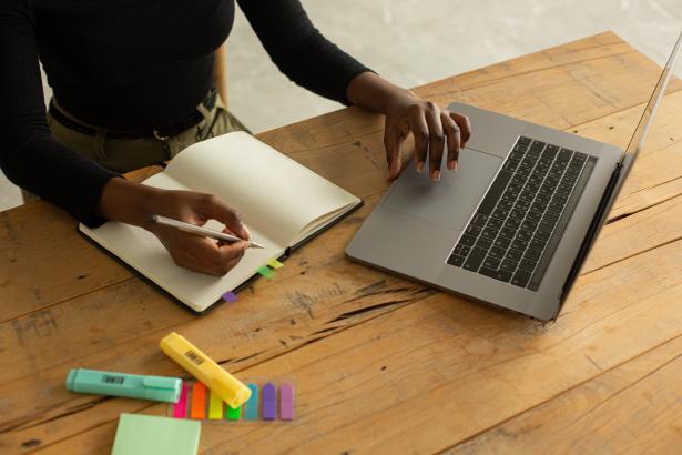 Handen schrijven notities en zitten op laptop