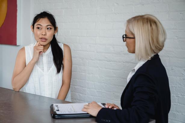 Een vrouw met Aziatische kenmerken wordt geïnterviewd door een blonde vrouw