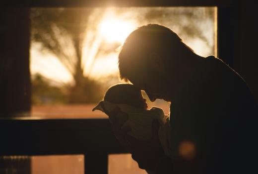 Silhouet van een man die een baby vasthoudt