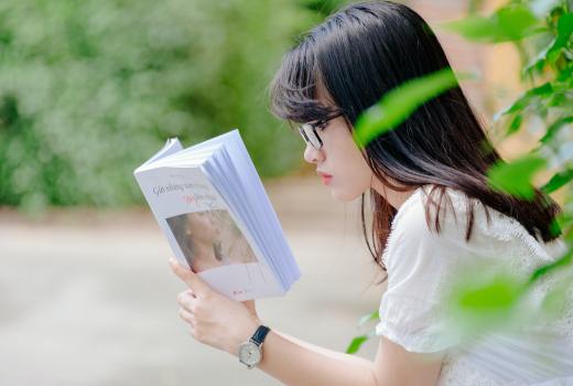 Vrouw met zwart haar en bril leest een wit boek
