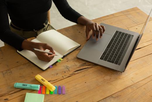 Handen schrijven notities en zitten op laptop